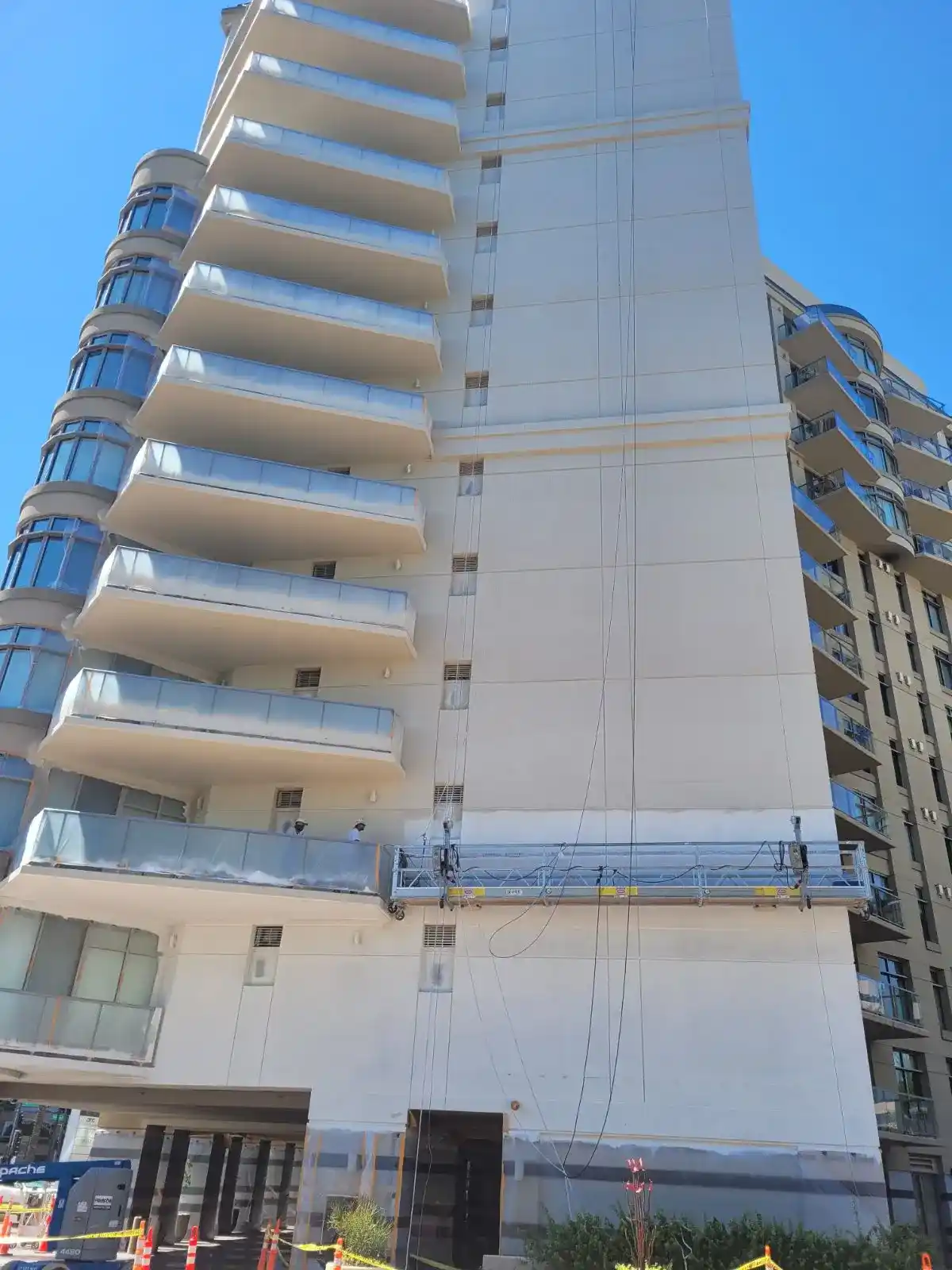 High-rise building being painted by professionals.