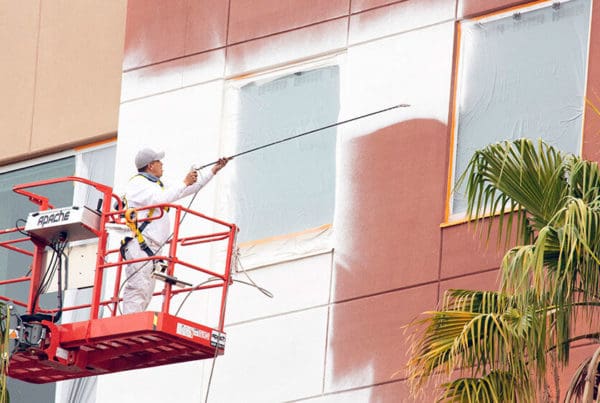 Ghaster painter using spray paint to paint the side of a building.