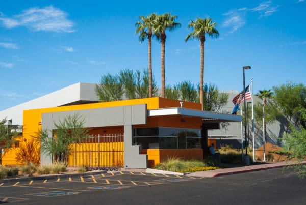 A newly painted yellow building with vibrant trees and an American flag flying nearby.