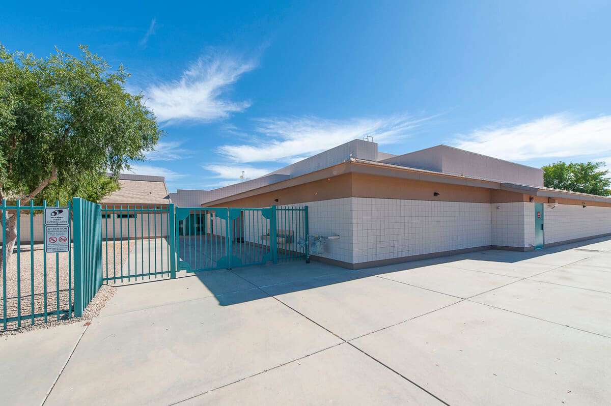 school with blue fence and parking lot