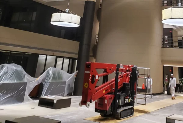 Inside a commercial building, painters setting up their machine lift to paint, highlighting their equipment and professional approach to the job.