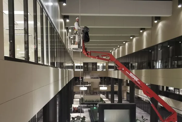 A painter using a lift to reach high ceilings while painting the interior of a space, demonstrating precision and skill in the task.