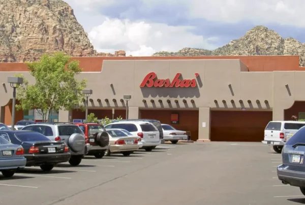 A view of Bashas Supermarket from outside the parking area, prominently featuring the Bashas logo on the building facade.