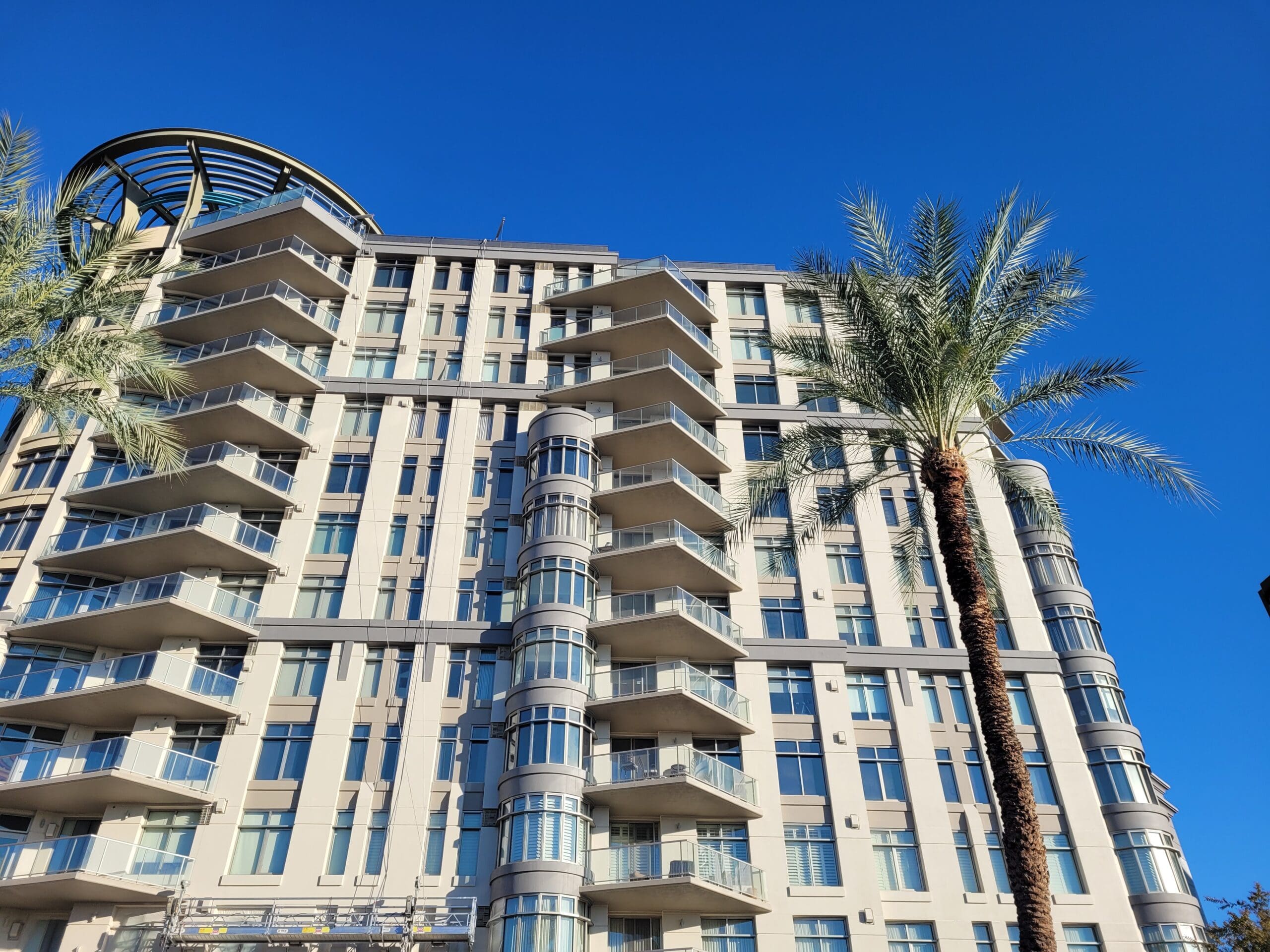 Exterior view of a modern commercial building with freshly painted walls in a sleek, professional finish, under a clear blue sky.