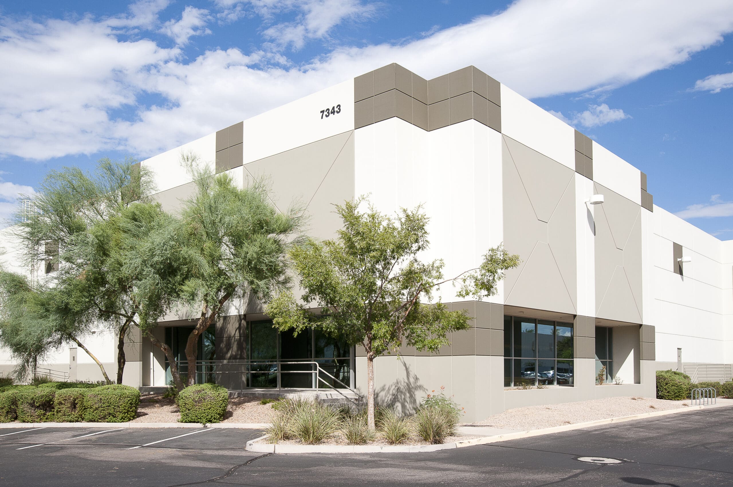 Exterior view of a modern commercial building with freshly painted walls in a sleek, professional finish, under a clear blue sky.